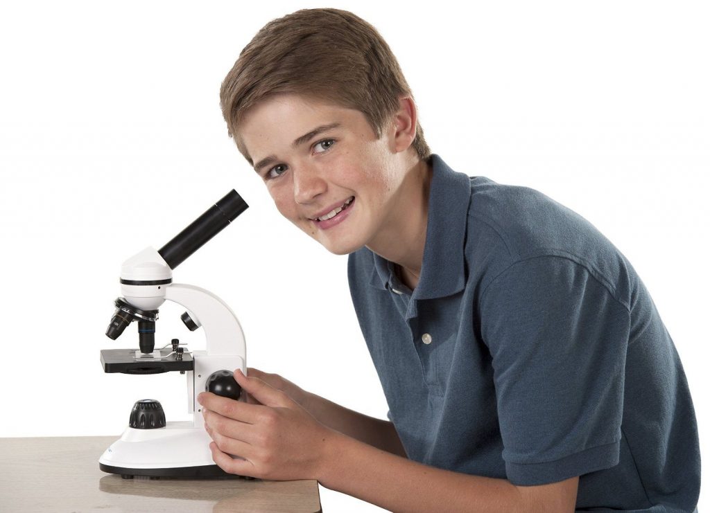 jovem rapaz a olhar através de um microscópio